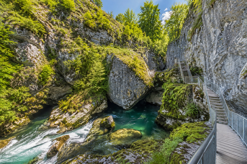 Passerelle aménagée au cœur des Pertes de l'Ain entre falaises calcaires et eaux turquoise